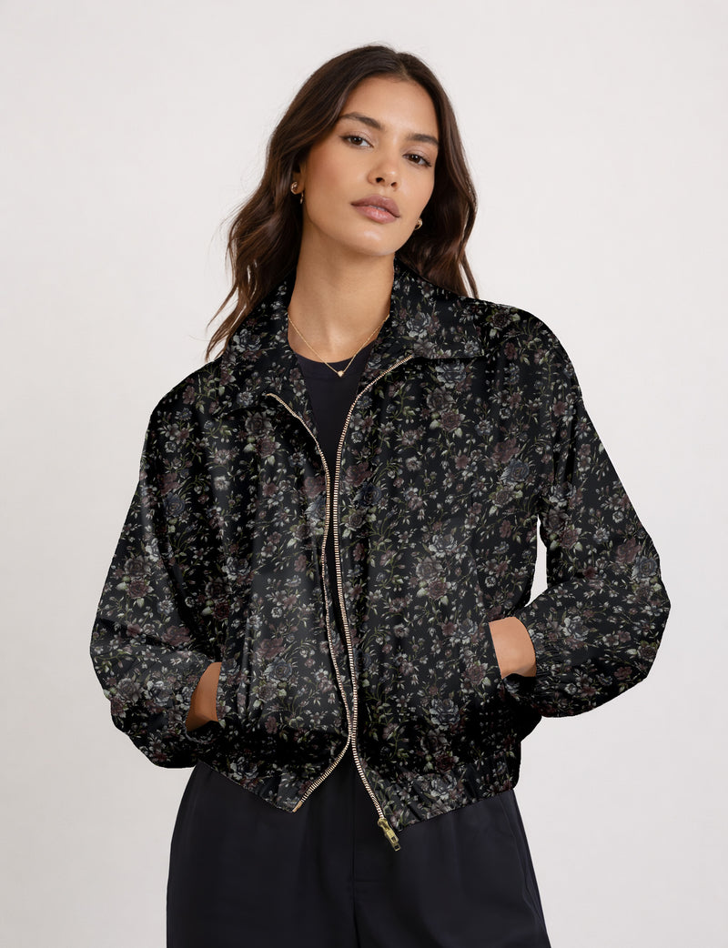 Brown floral bomber jacket with front zipper, elastic cuffs and hem, hanging on white hanger, red floral inner lining visible