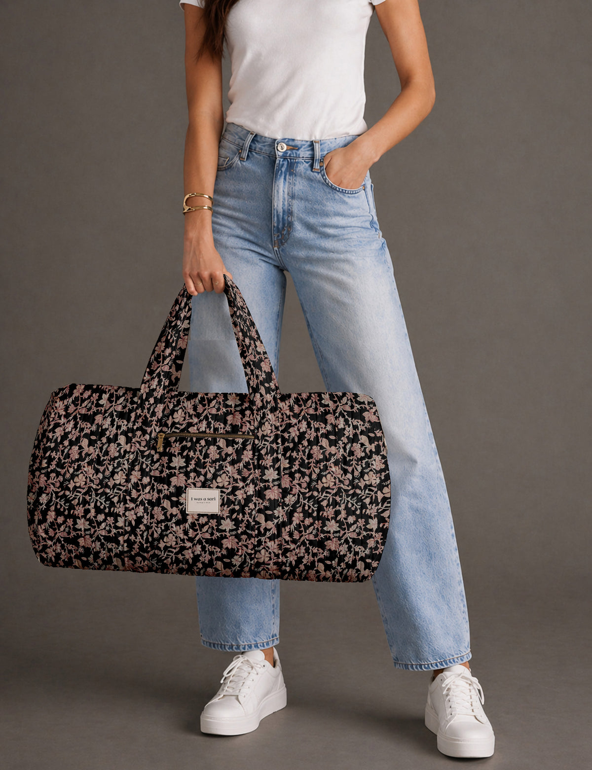 Quilted brown paisley barrel bag with double handles, front pocket, and gold zipper, shown in side angle view
