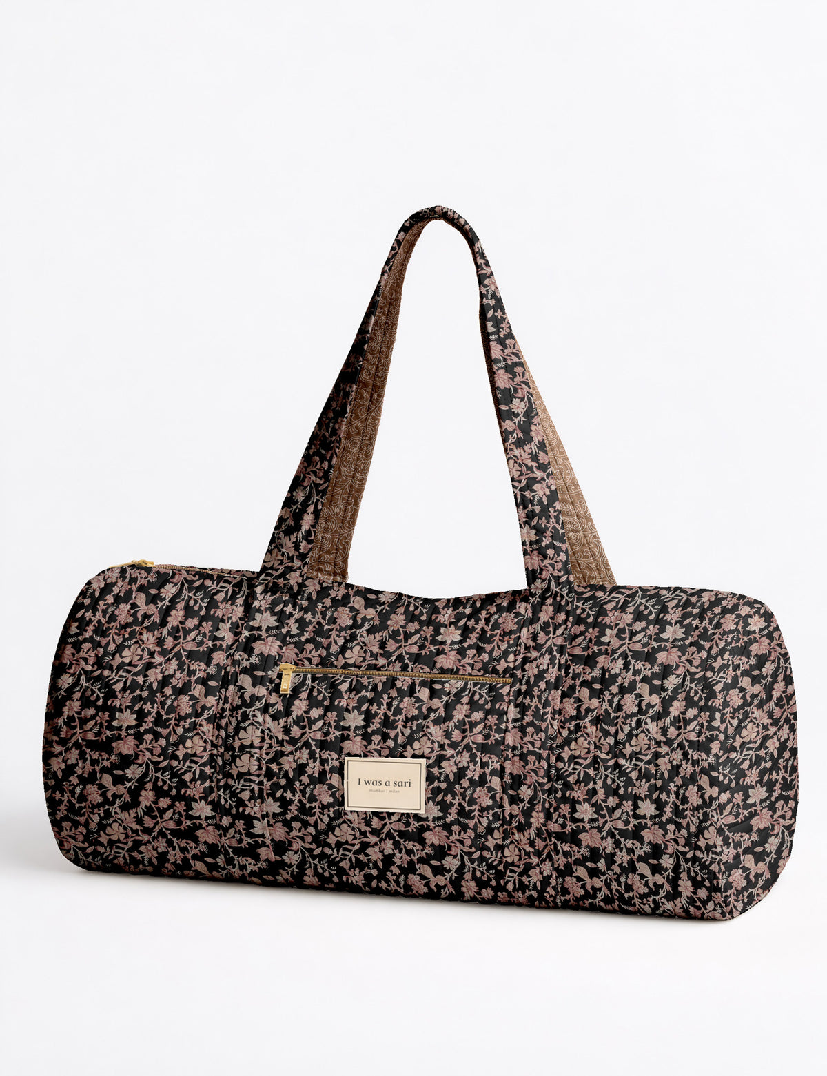 Brown paisley quilted bowling bag with front zipper pocket, held by person wearing white shirt and light blue jeans
