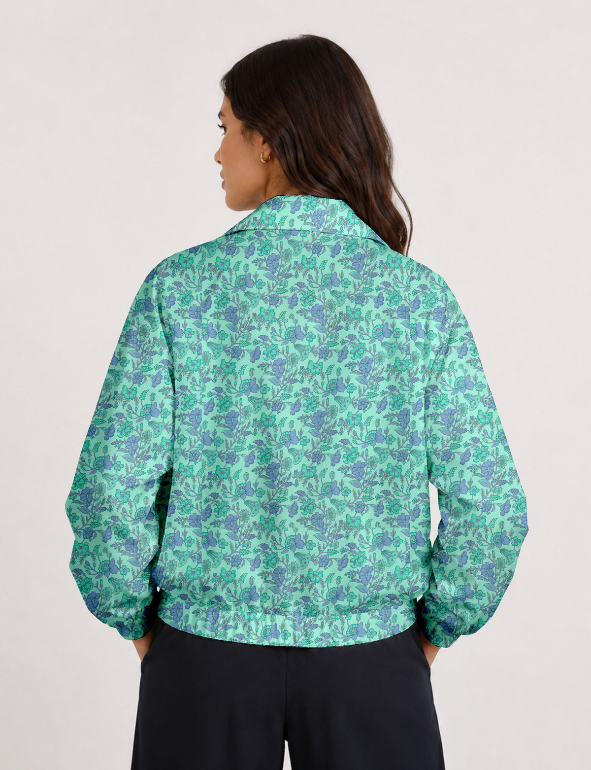 Woman wearing a yellow floral bomber jacket with front zipper, elastic cuffs, and side pockets, shown from front view