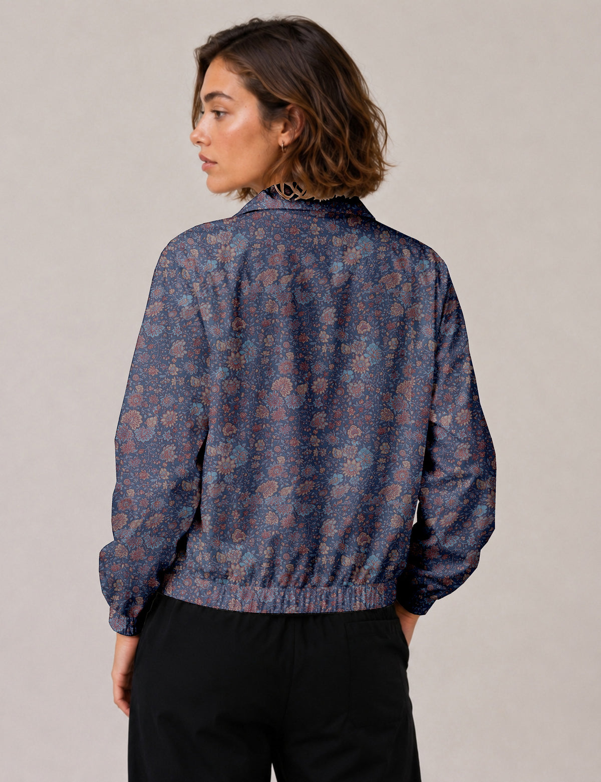 Woman wearing a yellow floral bomber jacket with front zipper, elastic cuffs, and side pockets, shown from front view