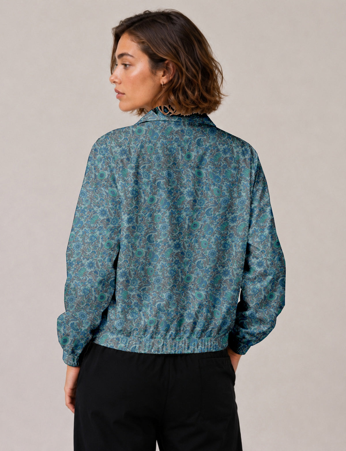Brown floral bomber jacket with front zipper, elastic cuffs and hem, hanging on white hanger, red floral inner lining visible