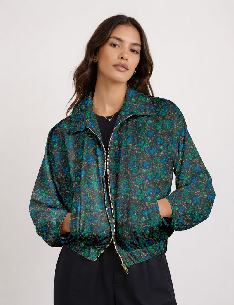 Brown floral bomber jacket with front zipper, elastic cuffs and hem, hanging on white hanger, red floral inner lining visible