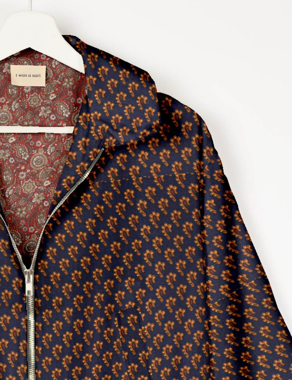 Blue bomber jacket with orange micro paisley pattern, silver zipper, and red paisley patterned inner lining with "I was a