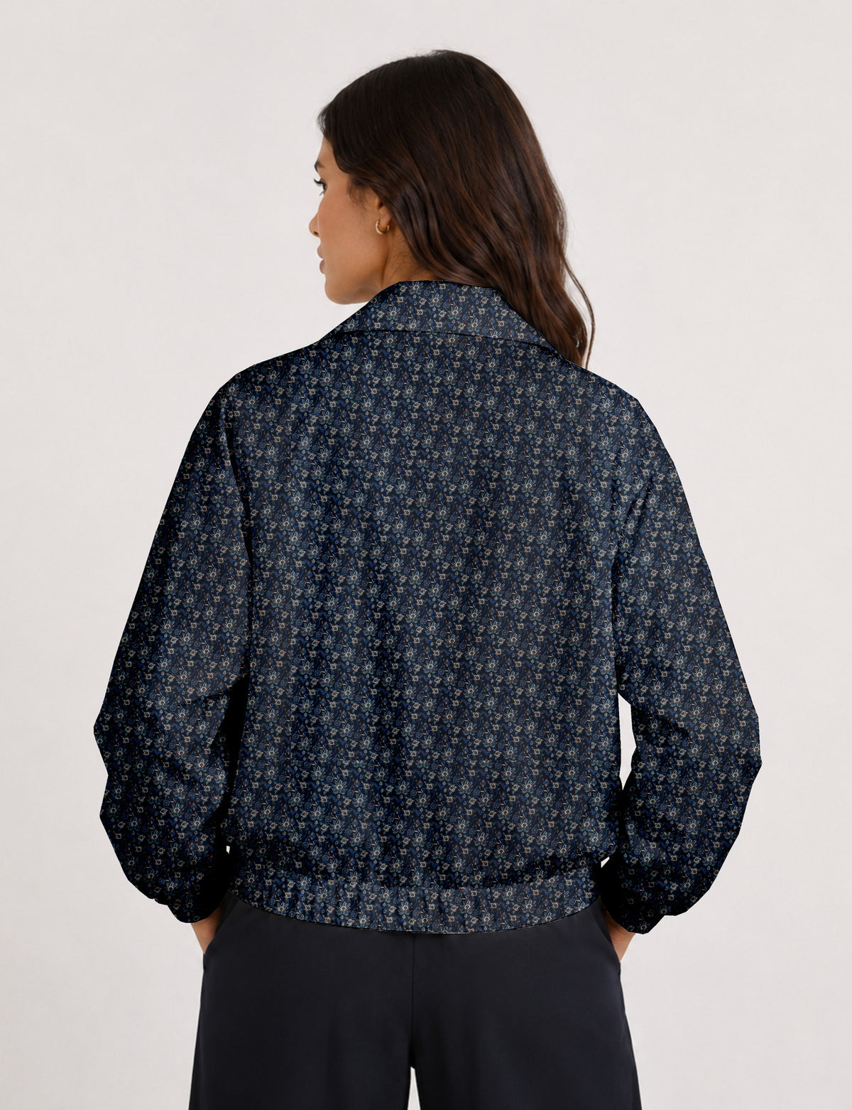 Brown floral bomber jacket with front zipper, elastic cuffs and hem, hanging on white hanger, red floral inner lining visible