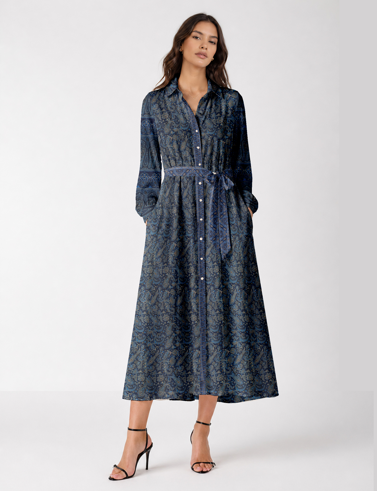 Woman wearing a long blue paisley shirt dress with button front, collar, long sleeves, and a matching fabric belt tied at