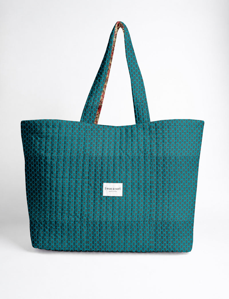 Quilted yellow tropical patterned beach bag with long handles and white label reading "I was a sari" front view