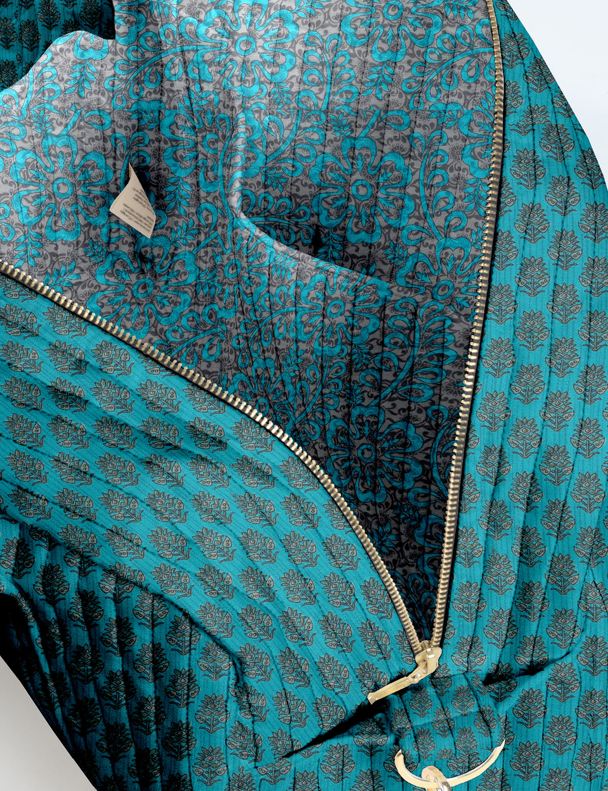 Brown quilted duffle bag with paisley pattern, front zip pocket, dual handles, and label reading "I was a sari"