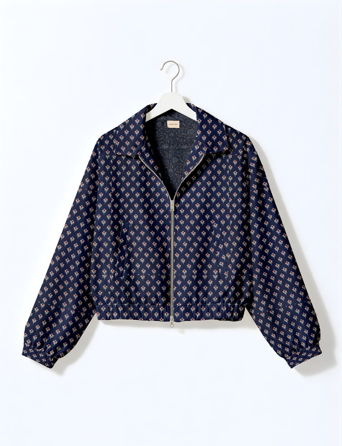 Brown floral bomber jacket with front zipper, elastic cuffs and hem, hanging on white hanger, red floral inner lining visible