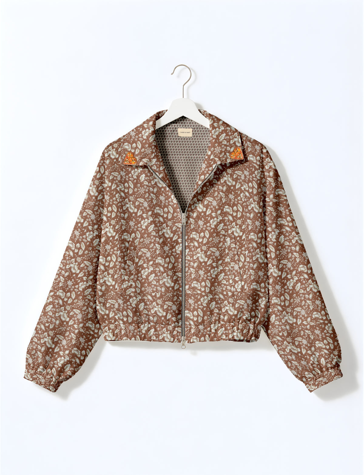 Brown floral bomber jacket with front zipper and gold heart patches on collar, shown on hanger, front view
