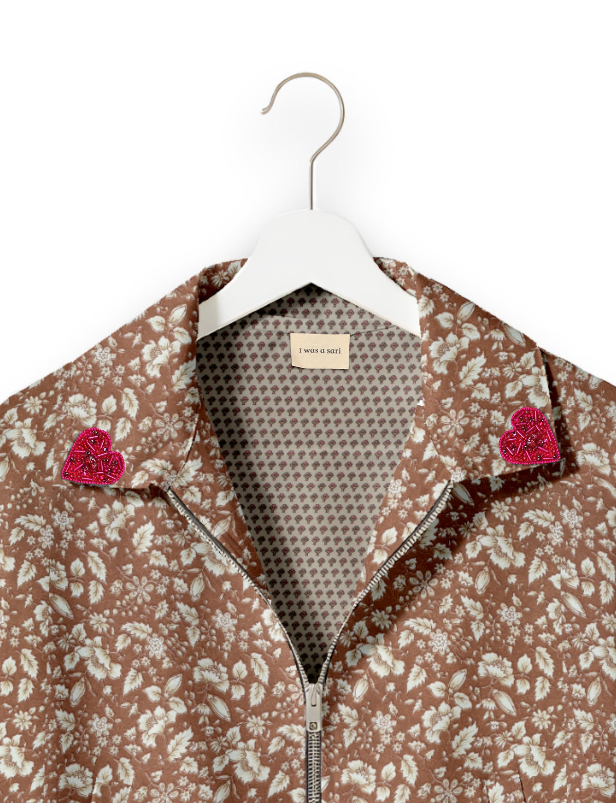 Brown floral bomber jacket with front zipper, pink beaded heart patches on collar, and "I was a sari" label inside collar