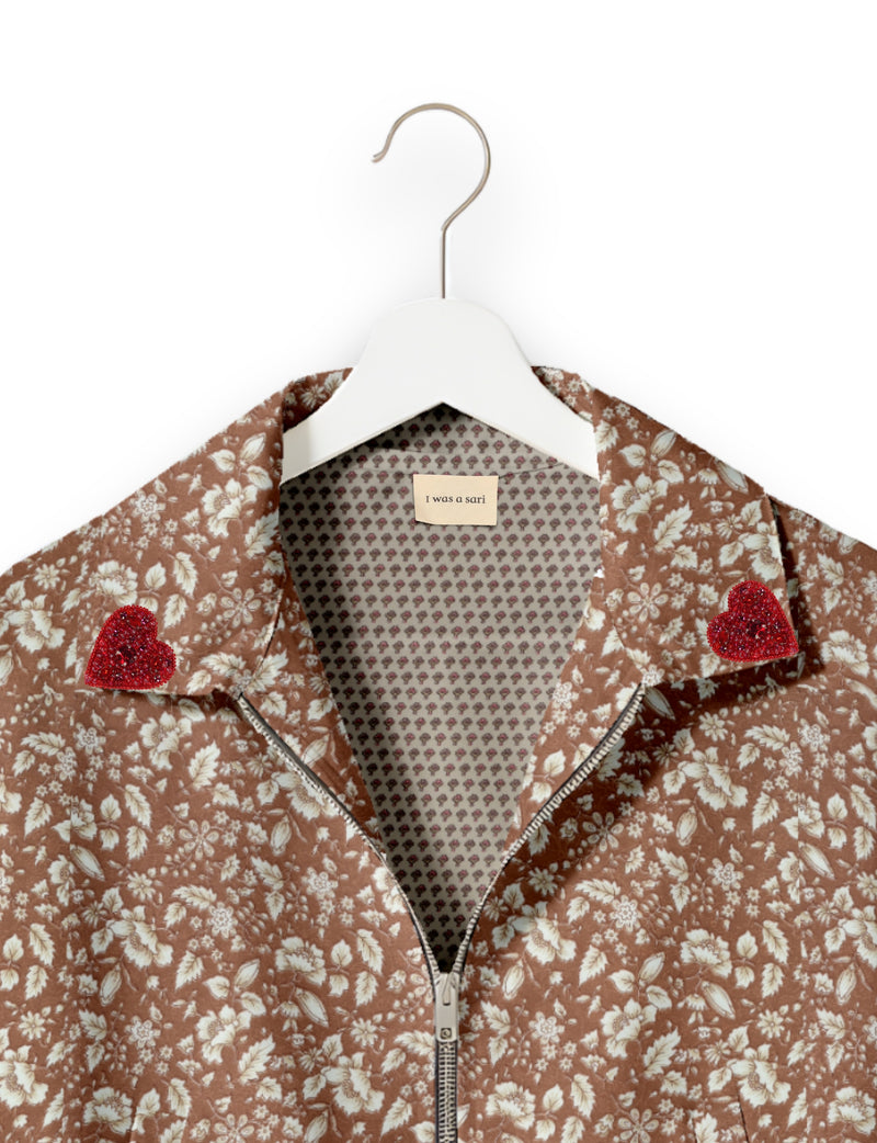 Brown floral bomber jacket with silver zipper, red beaded heart patches on collar, and "I was a sari" label inside collar