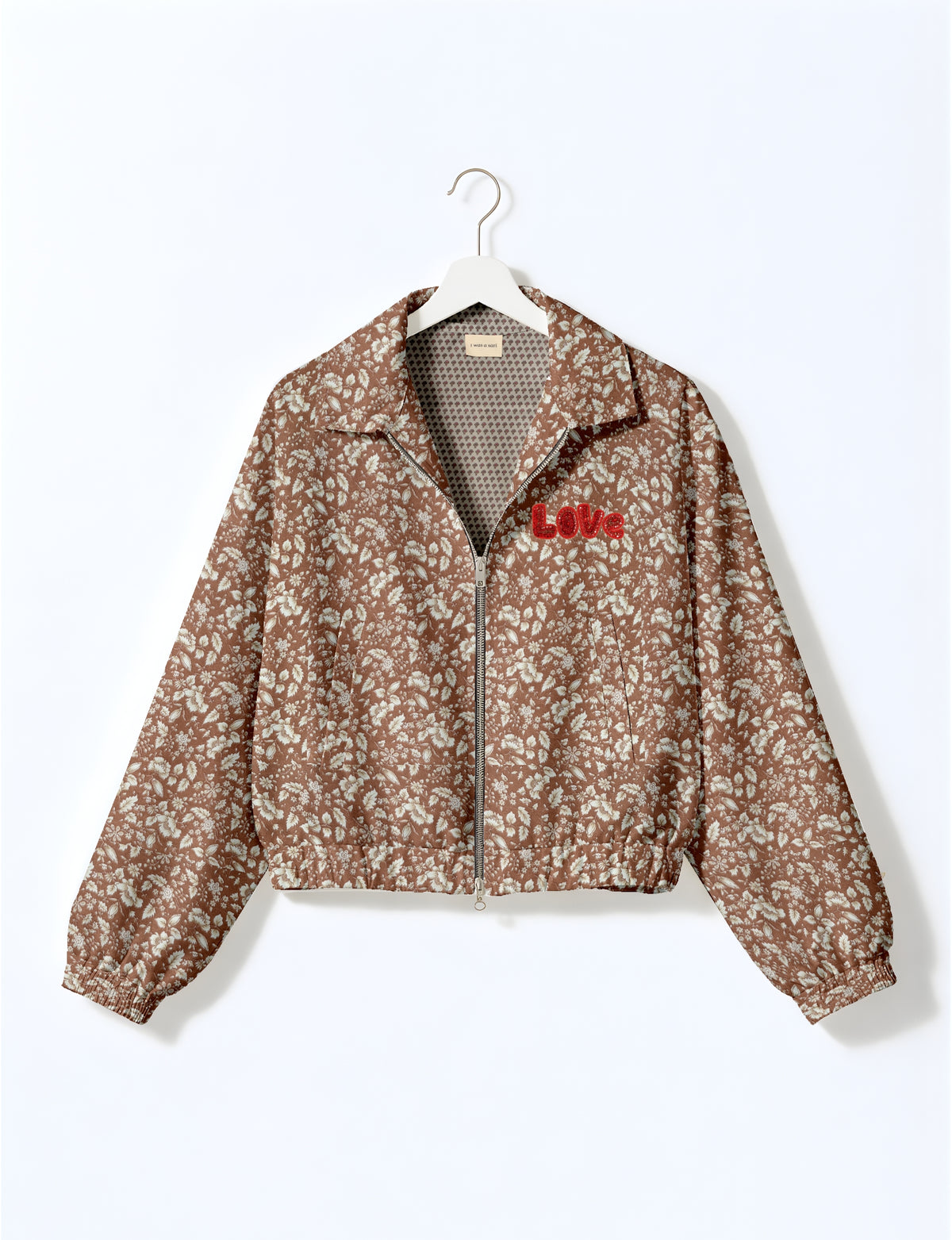 Brown floral bomber jacket with front zipper, elastic cuffs, and red "Love" embroidery on chest, hanging on white hanger