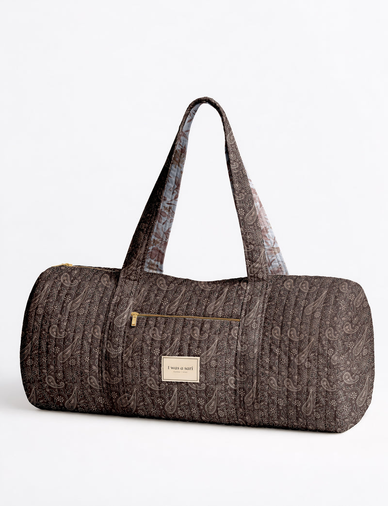 Brown paisley quilted bowling bag with dual handles, front zipper pocket, and "I was a sari" label on front side
