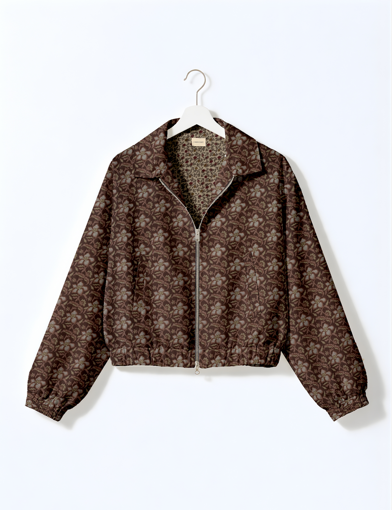 Brown bomber jacket with tropical floral pattern, front zipper, elastic cuffs and hem, hanging on white hanger front view