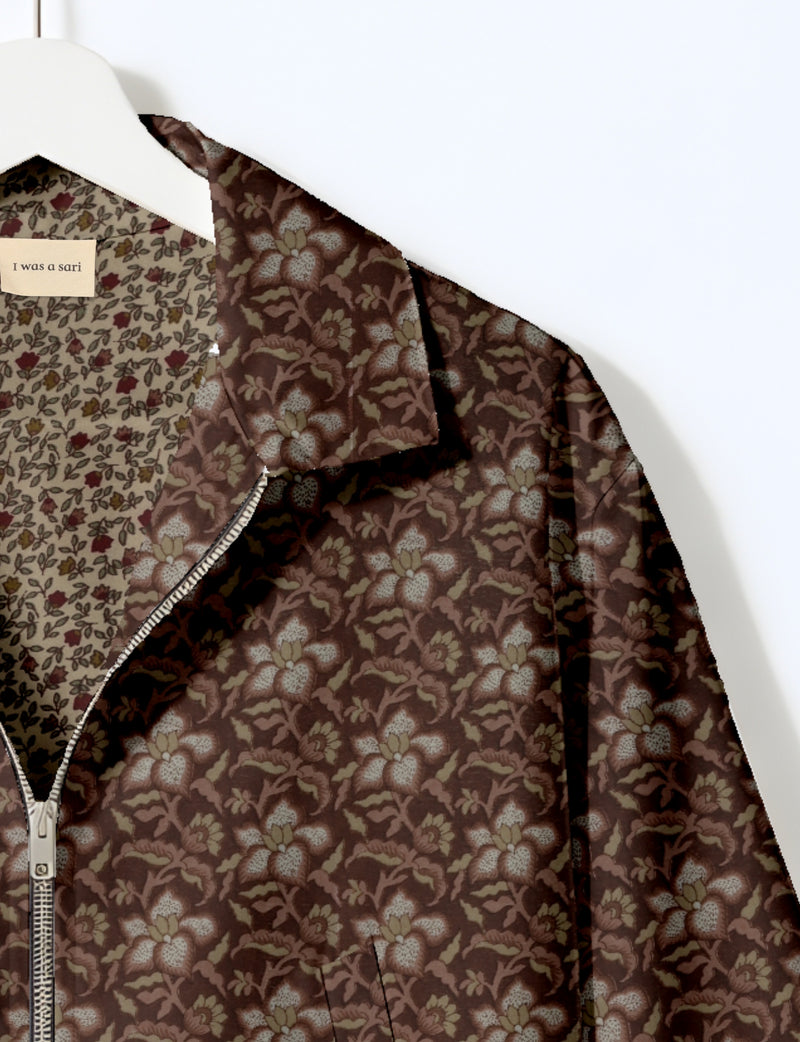 Brown bomber jacket with tropical floral pattern, silver zipper, and inner lining with smaller floral print on white hanger