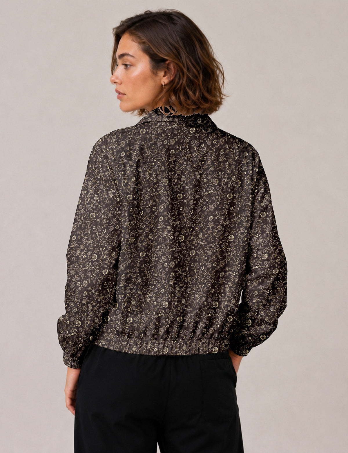 Brown floral bomber jacket with front zipper, elastic cuffs and hem, hanging on white hanger, red floral inner lining visible