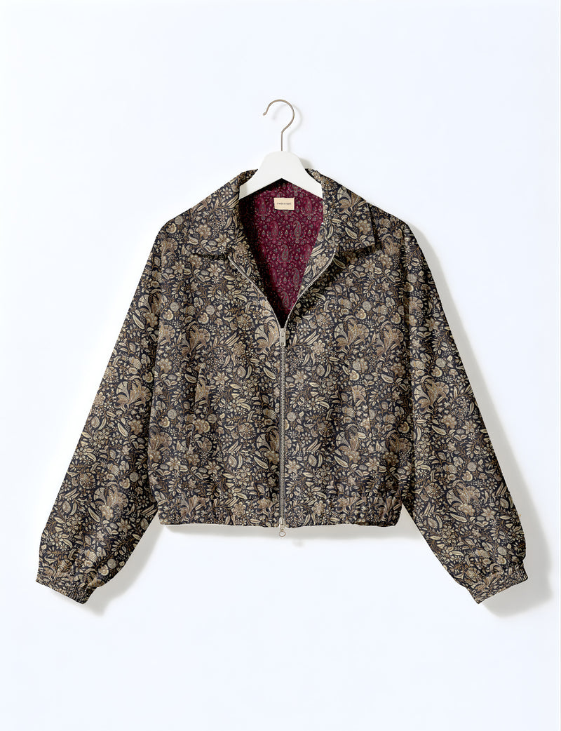 Brown floral bomber jacket with front zipper, elastic cuffs and hem, hanging on white hanger, red floral inner lining visible