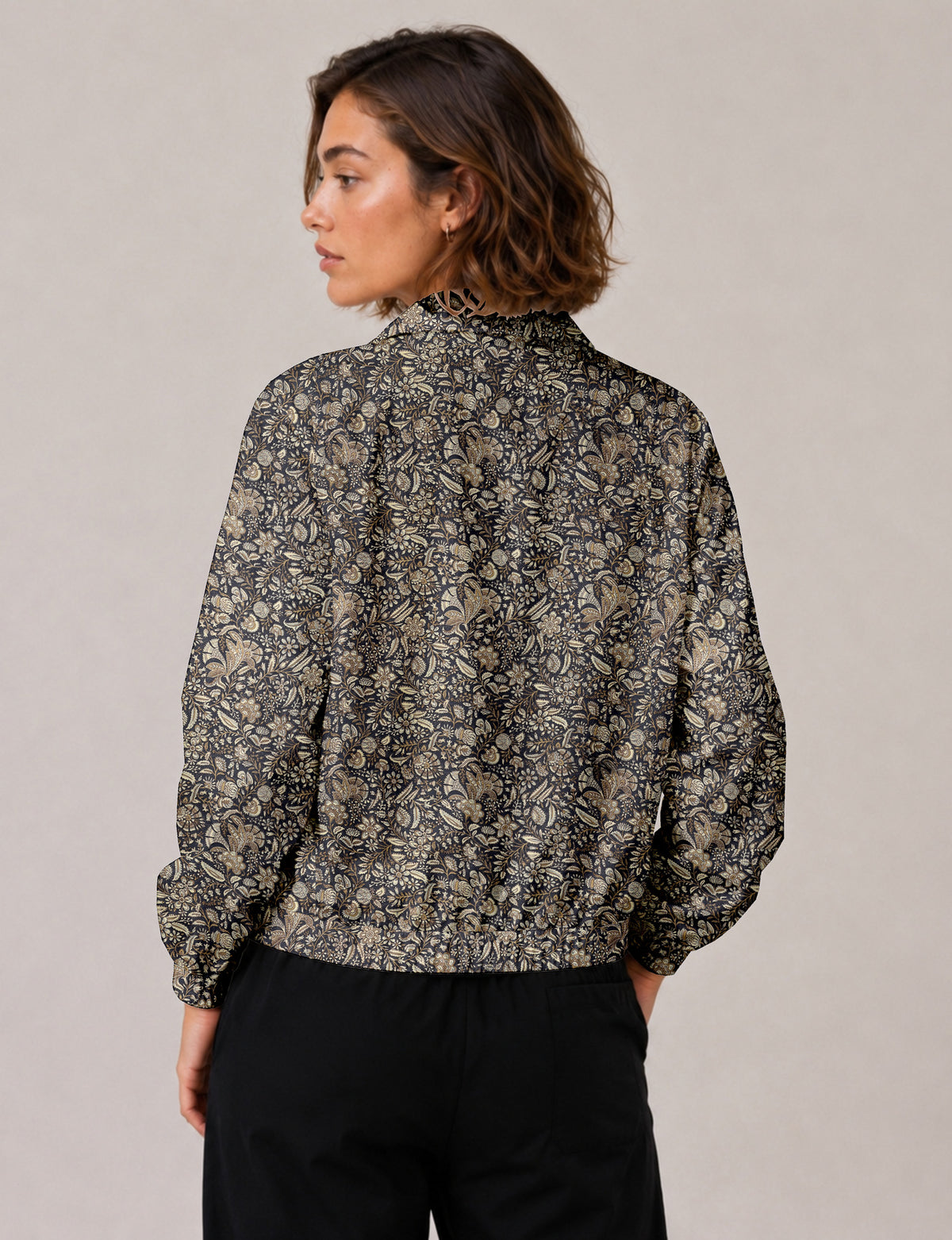 Woman wearing a yellow floral bomber jacket with front zipper, elastic cuffs, and side pockets, shown from front view