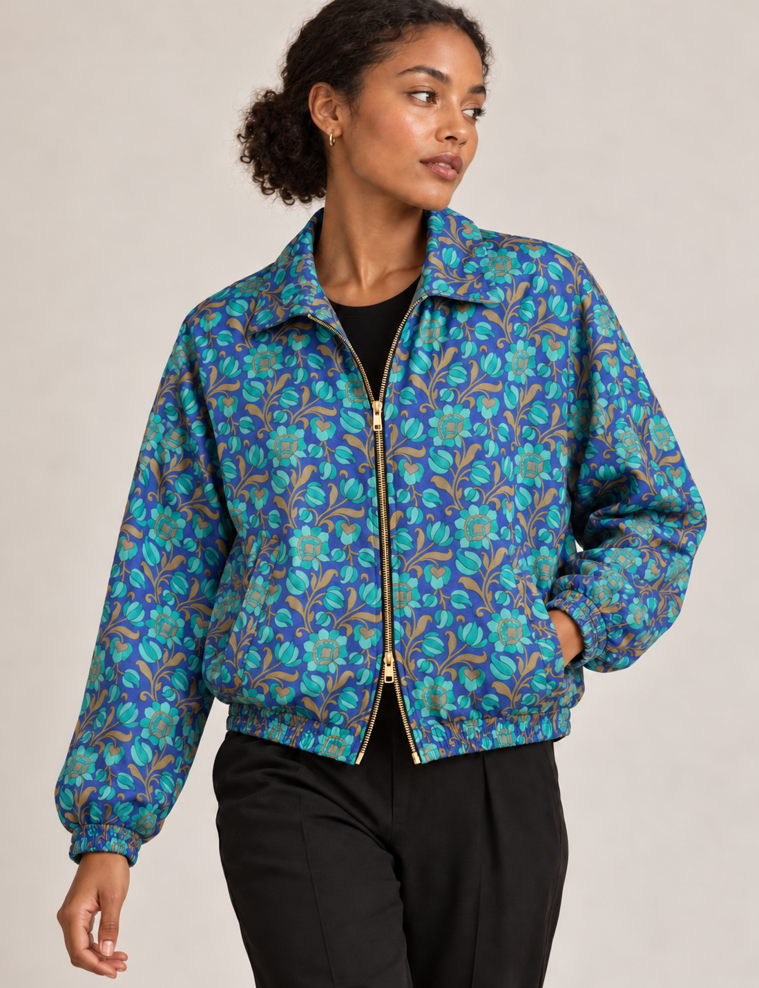 Woman wearing a yellow floral bomber jacket with front zipper, elastic cuffs, and side pockets, shown from front view