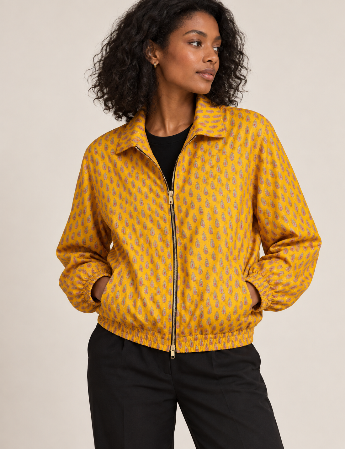 Woman wearing a yellow floral bomber jacket with front zipper, elastic cuffs, and side pockets, shown from front view