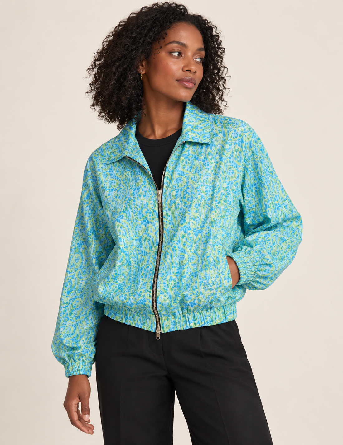 Woman wearing a yellow floral bomber jacket with front zipper, elastic cuffs, and side pockets, shown from front view