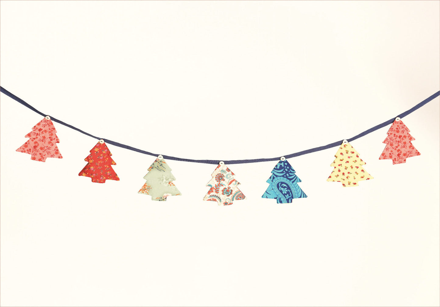 Eco-friendly Christmas bunting featuring Christmas tree patches made from recycled saris, attached to canvas lace with buttons. A sustainable, upcycled decoration promoting circular fashion and ethical holiday decor.