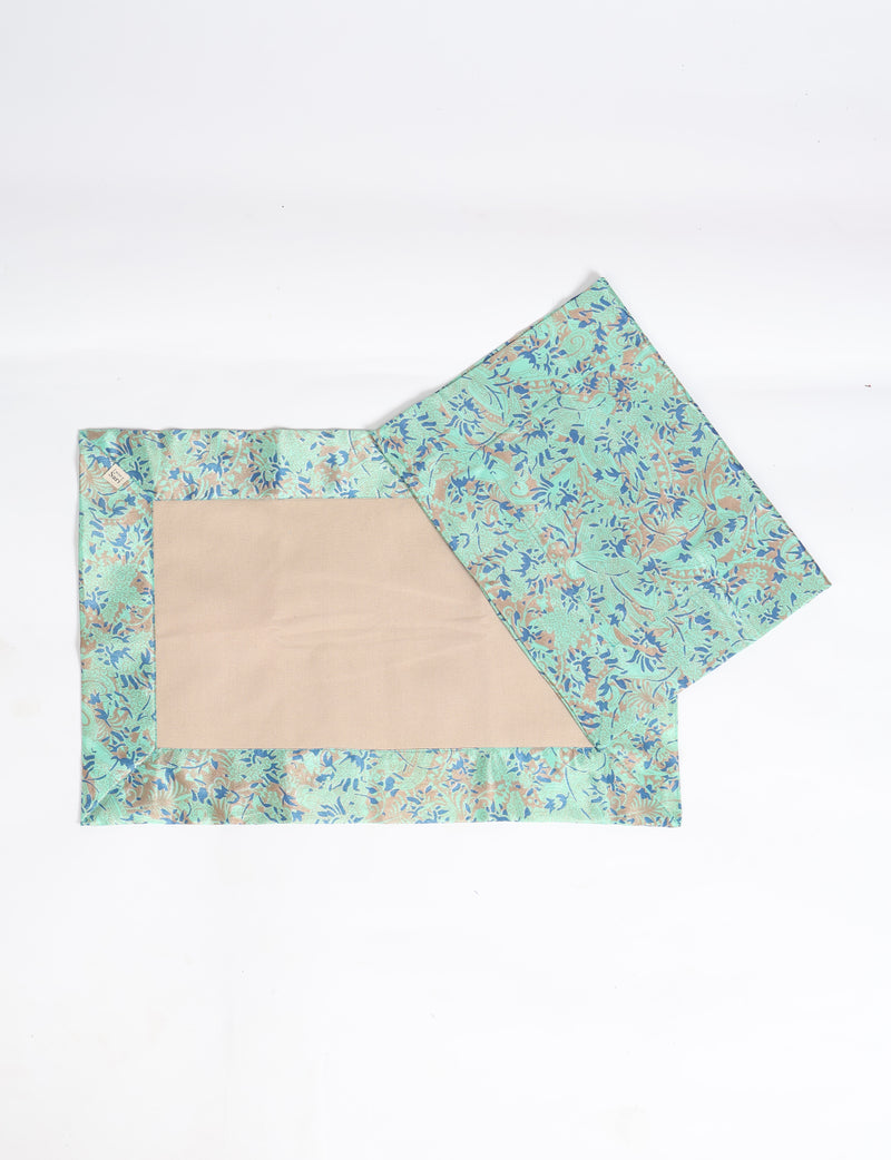 Set of two canvas placemats with green tropical floral border and beige center, flat lay on white background