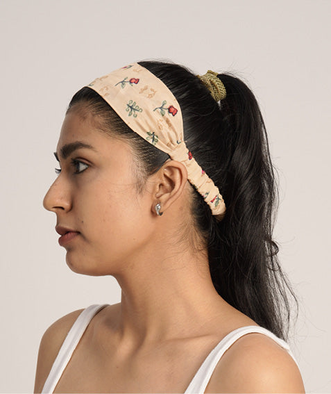 Woman wearing a beige elastic headband with small floral prints, styled with a green scrunchie in a ponytail