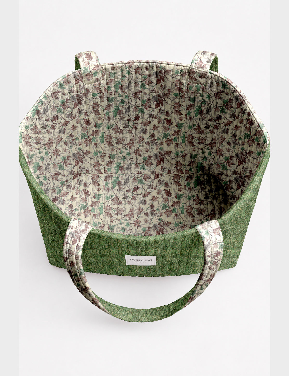 Quilted beach bag with yellow tropical exterior and red patterned interior, shown from top view with handles visible