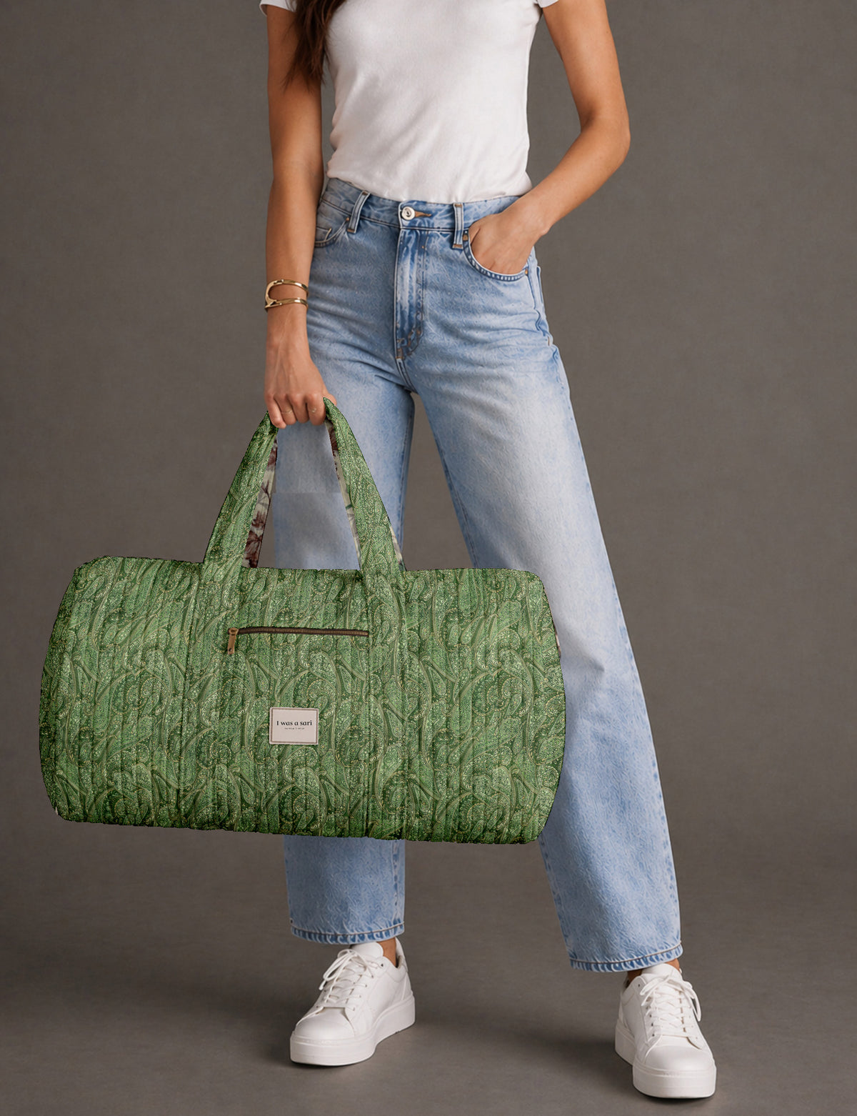 Quilted brown paisley barrel bag with double handles, front pocket, and gold zipper, shown in side angle view