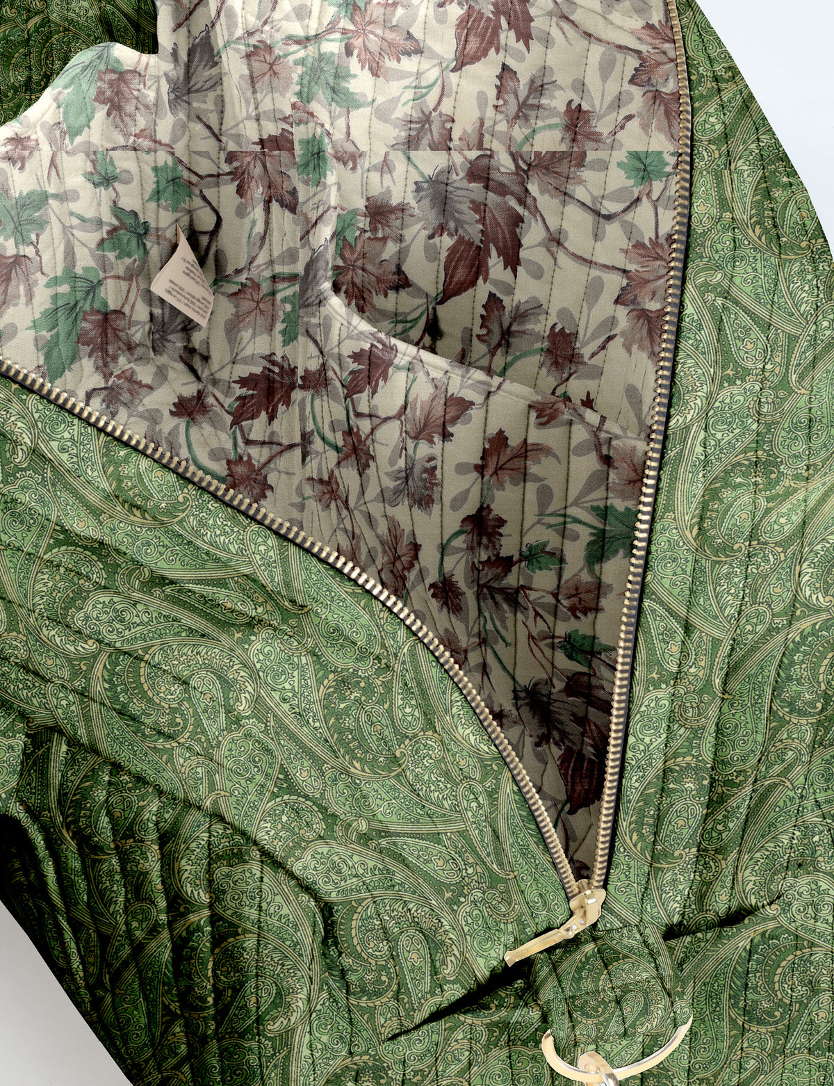 Brown quilted duffle bag with paisley pattern, front zip pocket, dual handles, and label reading "I was a sari"