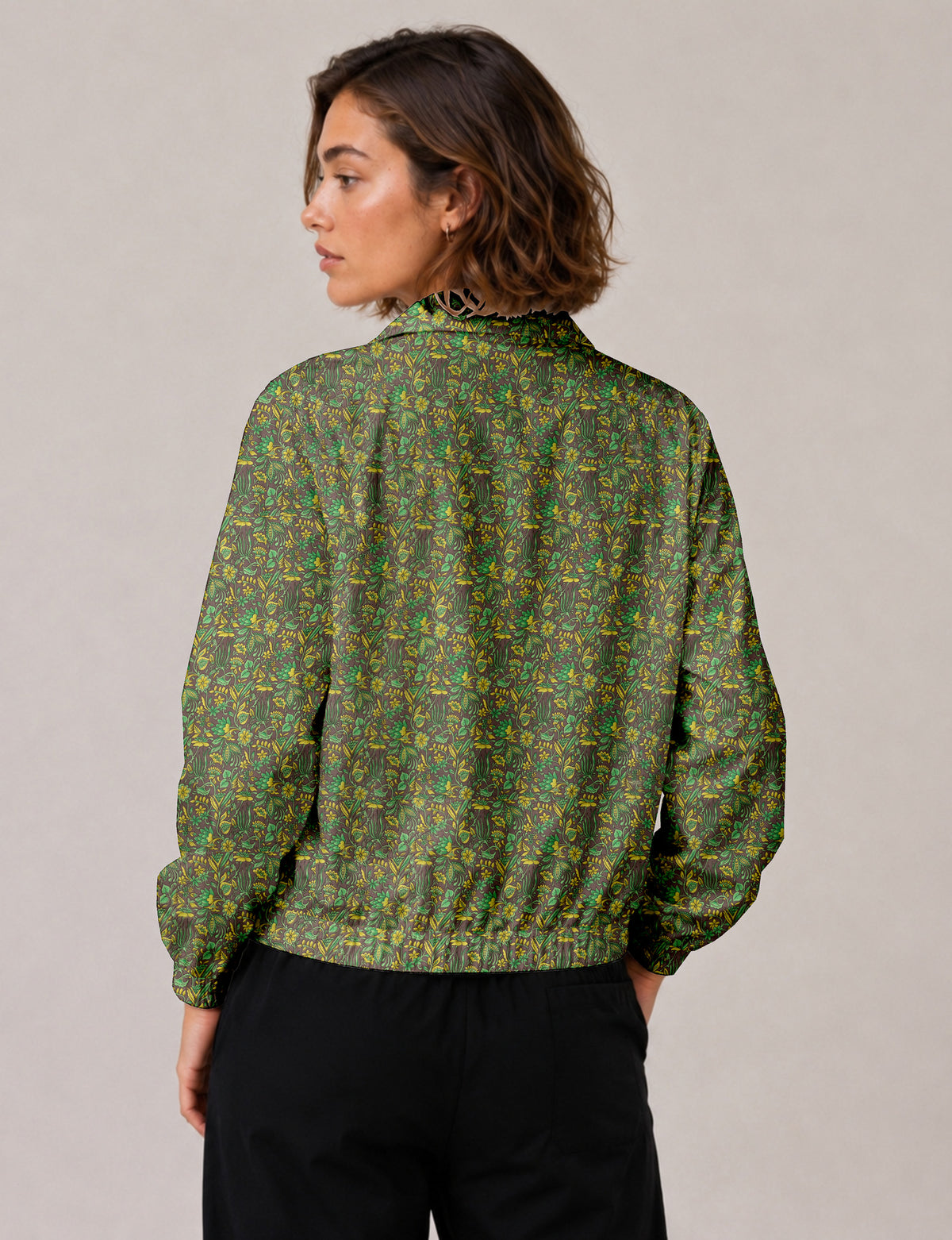 Woman wearing a yellow floral bomber jacket with front zipper, elastic cuffs, and side pockets, shown from front view