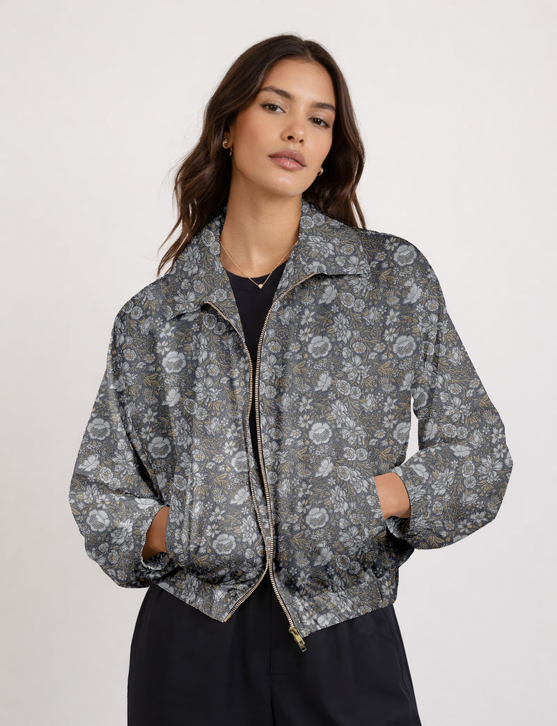 Brown floral bomber jacket with front zipper, elastic cuffs and hem, hanging on white hanger, red floral inner lining visible