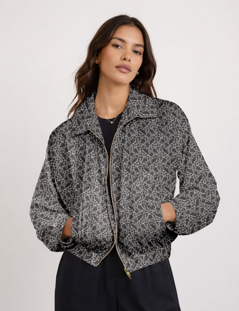 Woman wearing a yellow floral bomber jacket with front zipper, elastic cuffs, and side pockets, shown from front view