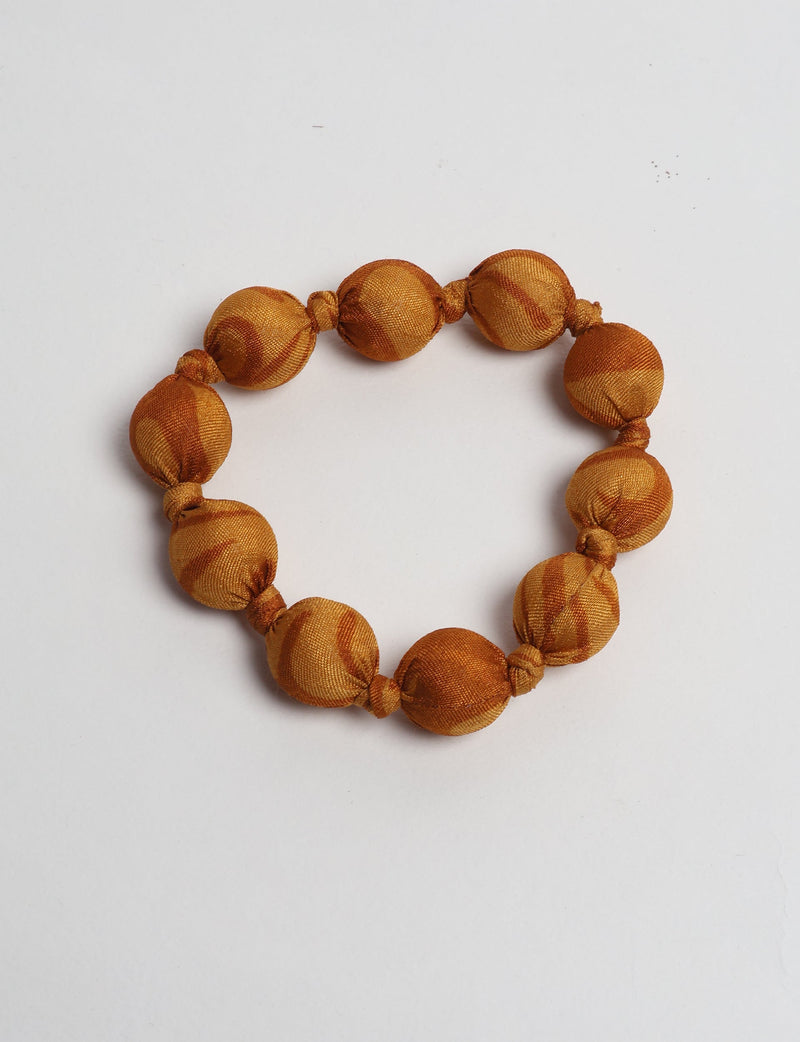 Orange tropical beaded bracelet with knotted fabric-covered round beads, shown flat on a white background