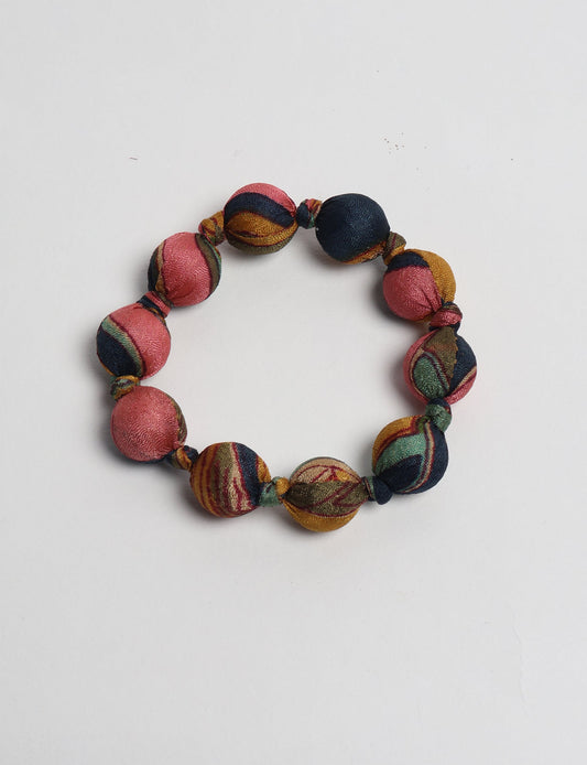 Eco friendly beaded knotted bracelet crafted from upcycled women’s clothing and repurposed sari fabrics, showcasing circular fashion and sustainable apparel.