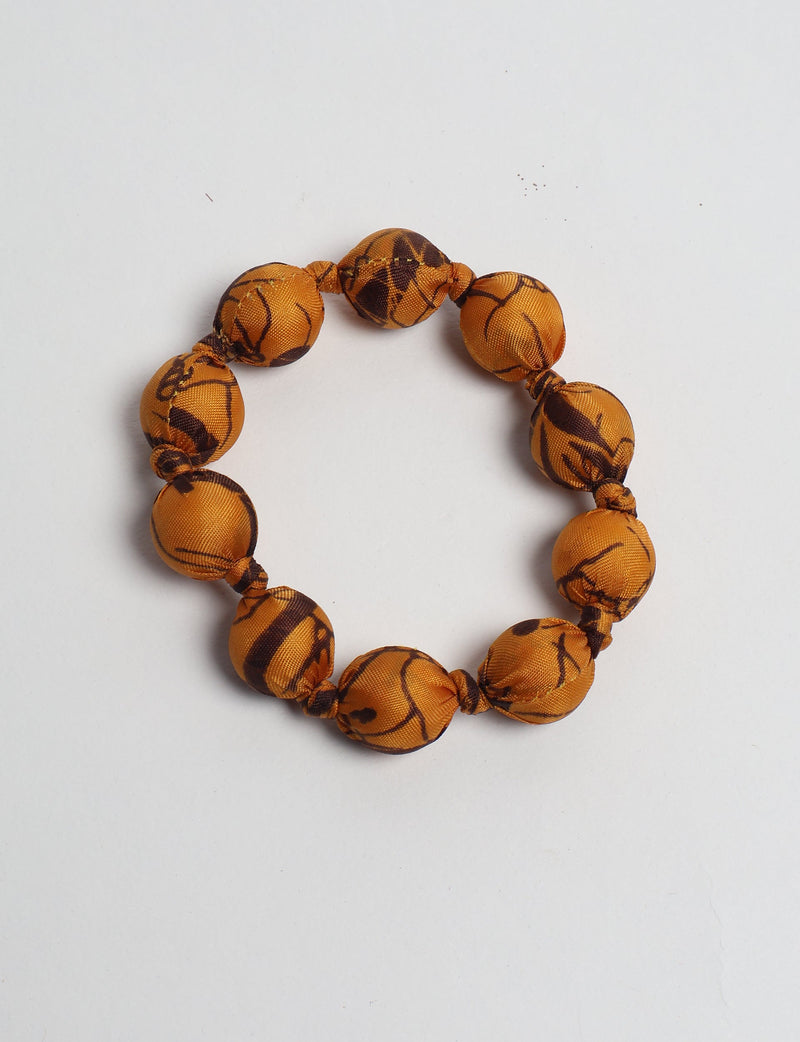 Yellow tropical fabric beaded bracelet with knotted details, shown flat on a white background