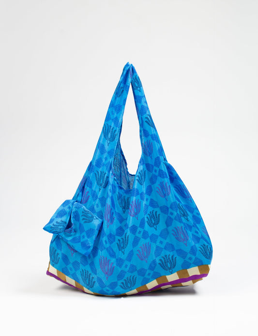 Stay eco-conscious with our Reusable Bag, handmade by Indian artisans from pre-loved saris. Silky and lightweight, this foldaway bag is perfect for your on-the-go lifestyle. Each piece is a unique statement of ethical fashion, embracing sustainability and style.