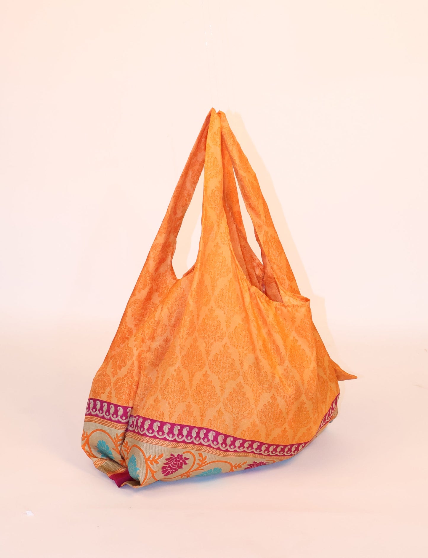 Stay eco-conscious with our Reusable Bag, handmade by Indian artisans from pre-loved saris. Silky and lightweight, this foldaway bag is perfect for your on-the-go lifestyle. Each piece is a unique statement of ethical fashion, embracing sustainability and style.