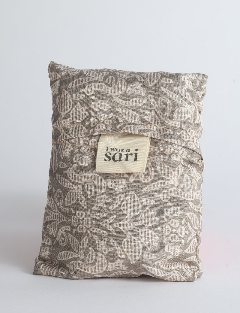 Blue reusable bag with multicolor tropical floral pattern folded with "I was a sari" label visible on front