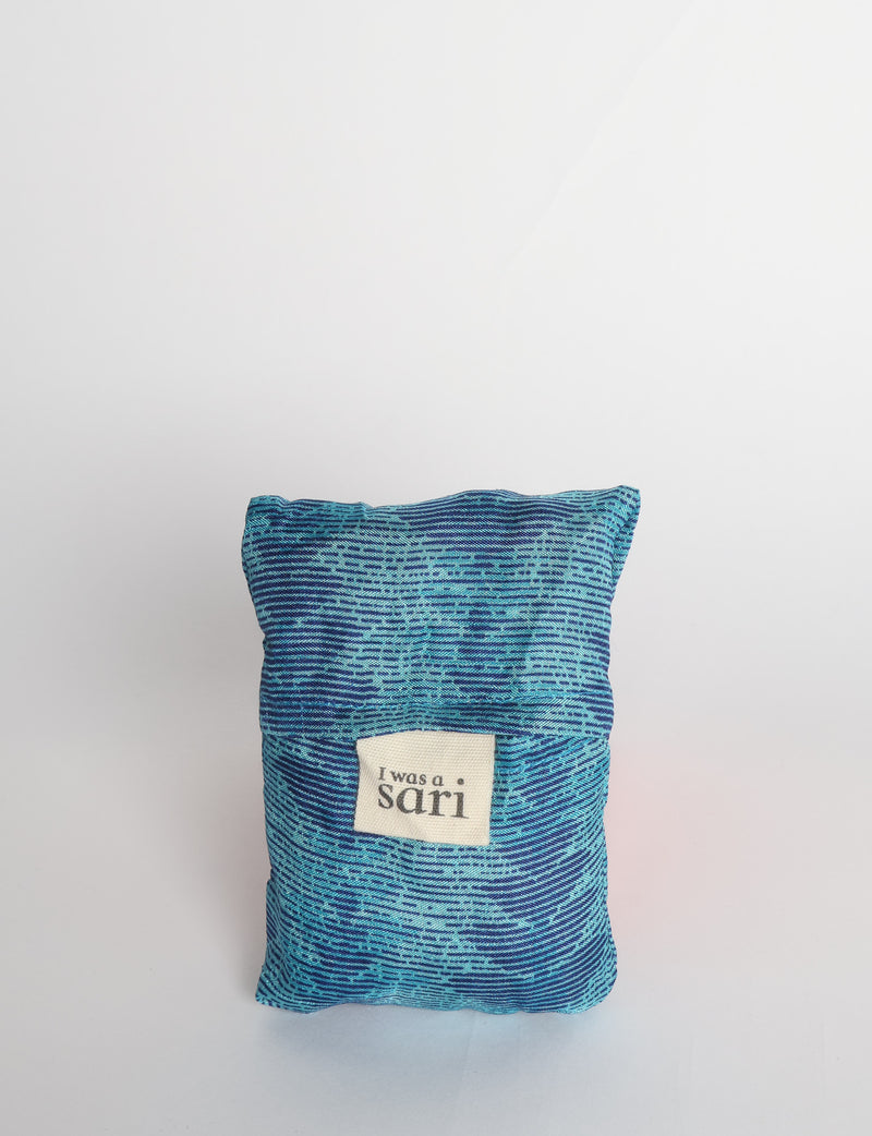 Blue reusable bag with multicolor tropical floral pattern folded with "I was a sari" label visible on front