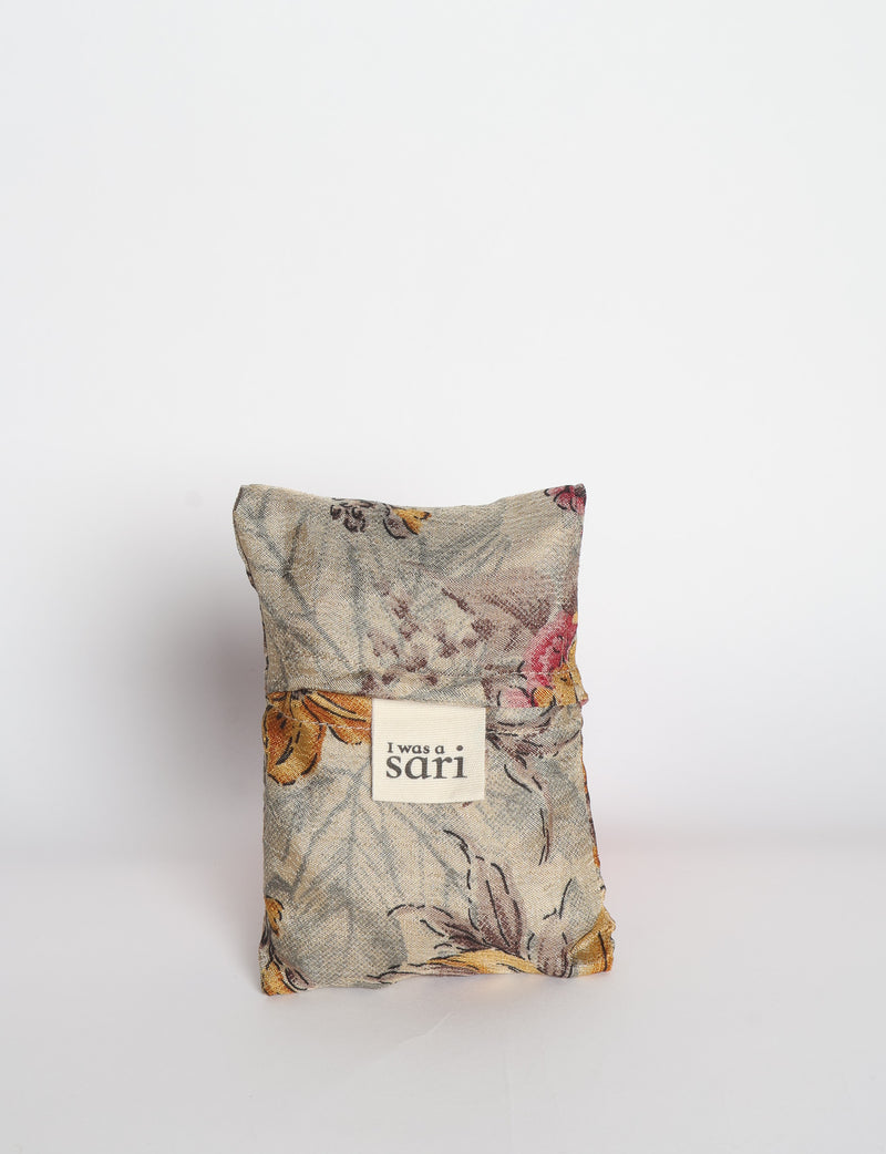 Blue reusable bag with multicolor tropical floral pattern folded with "I was a sari" label visible on front