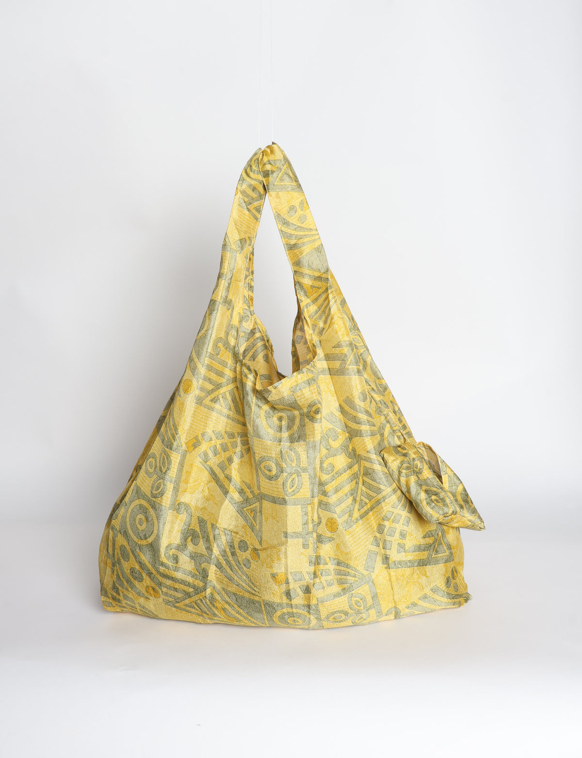 Blue reusable bag with tropical floral pattern in pink, yellow, and green, shown hanging with handles visible