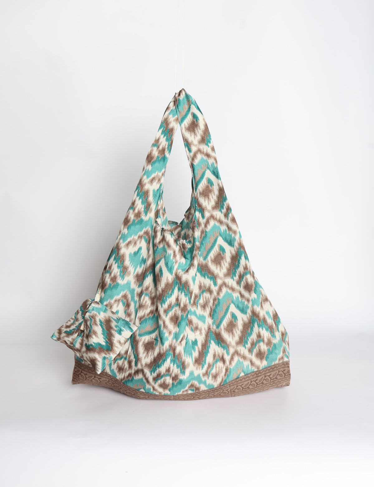 Blue reusable bag with tropical floral pattern in pink, yellow, and green, shown hanging with handles visible