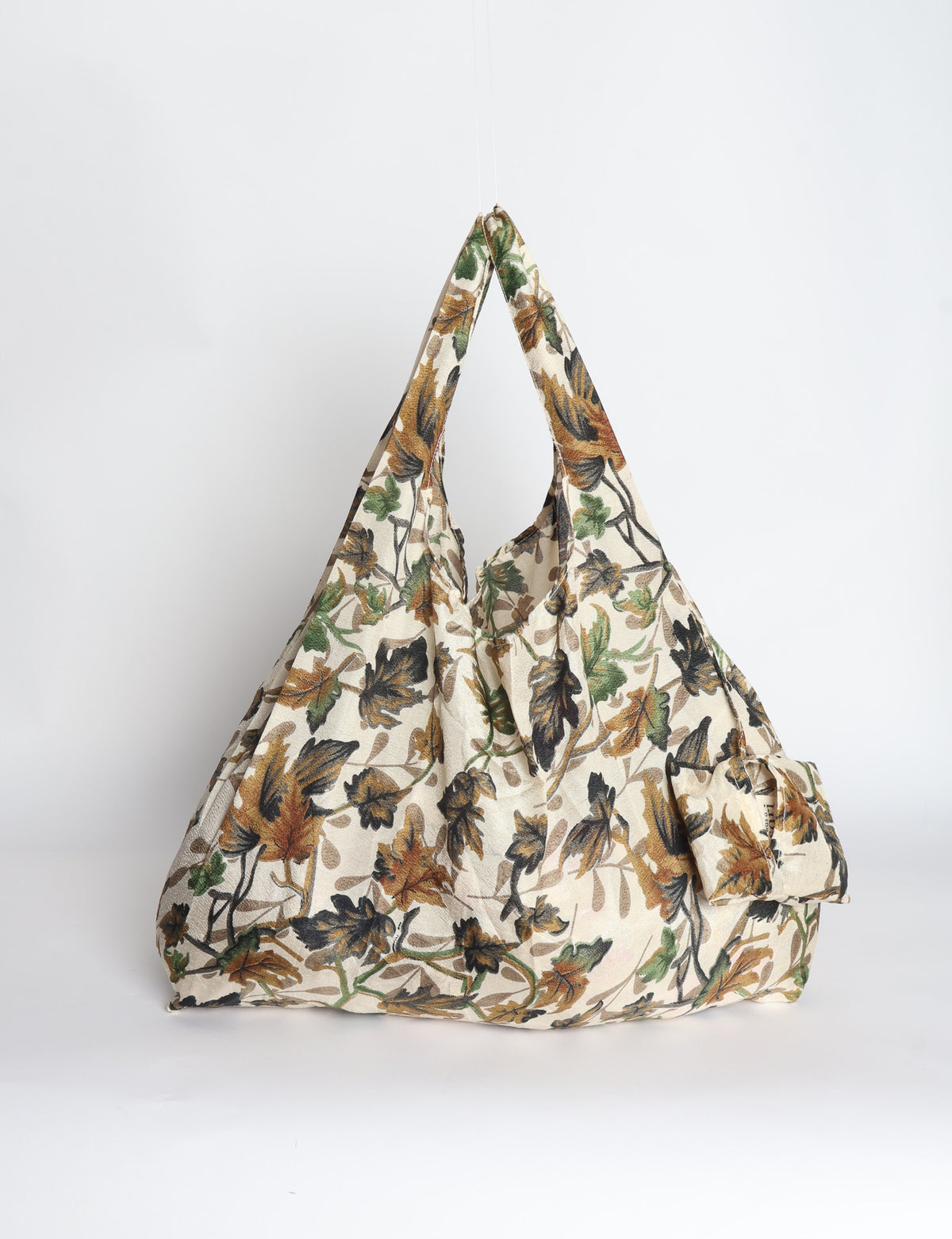 Blue reusable bag with tropical floral pattern in pink, yellow, and green, shown hanging with handles visible