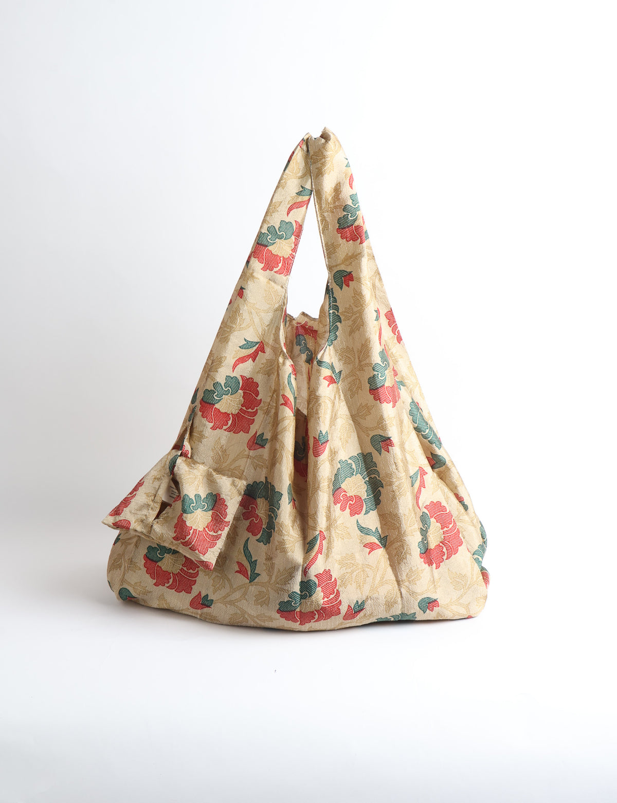 Blue reusable bag with tropical floral pattern in pink, yellow, and green, shown hanging with handles visible