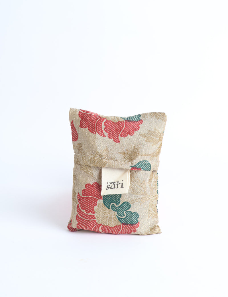Blue reusable bag with multicolor tropical floral pattern folded with "I was a sari" label visible on front