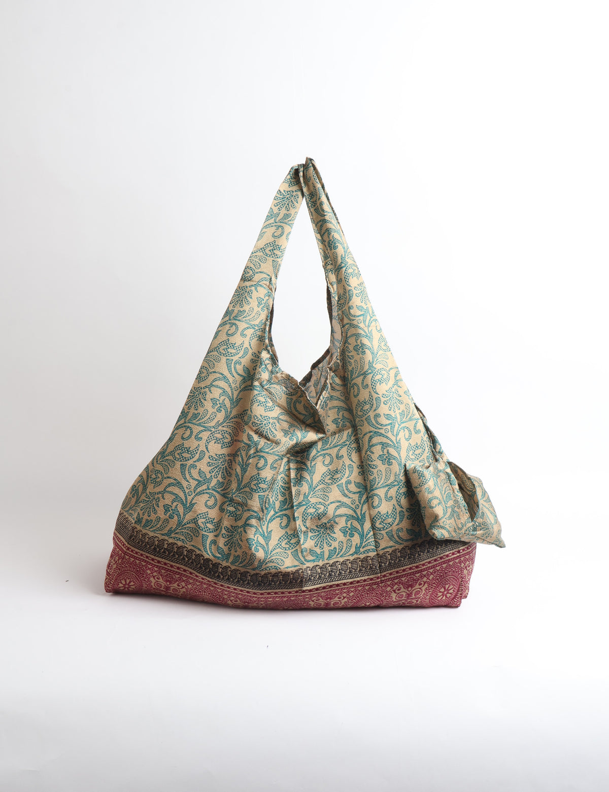 Blue reusable bag with tropical floral pattern in pink, yellow, and green, shown hanging with handles visible