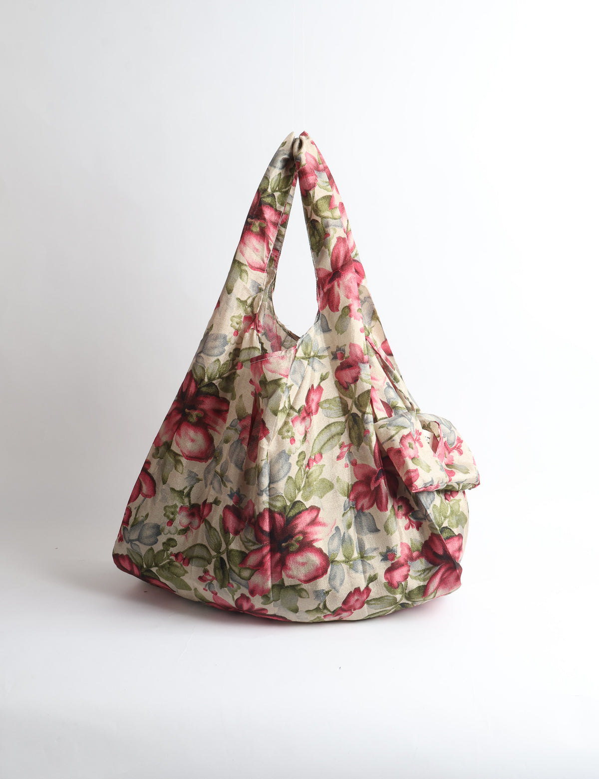 Blue reusable bag with tropical floral pattern in pink, yellow, and green, shown hanging with handles visible